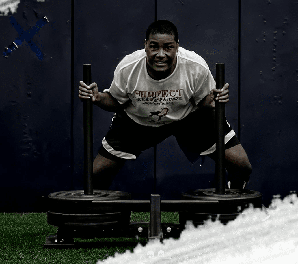 Man pushing weights on grass indoors.
