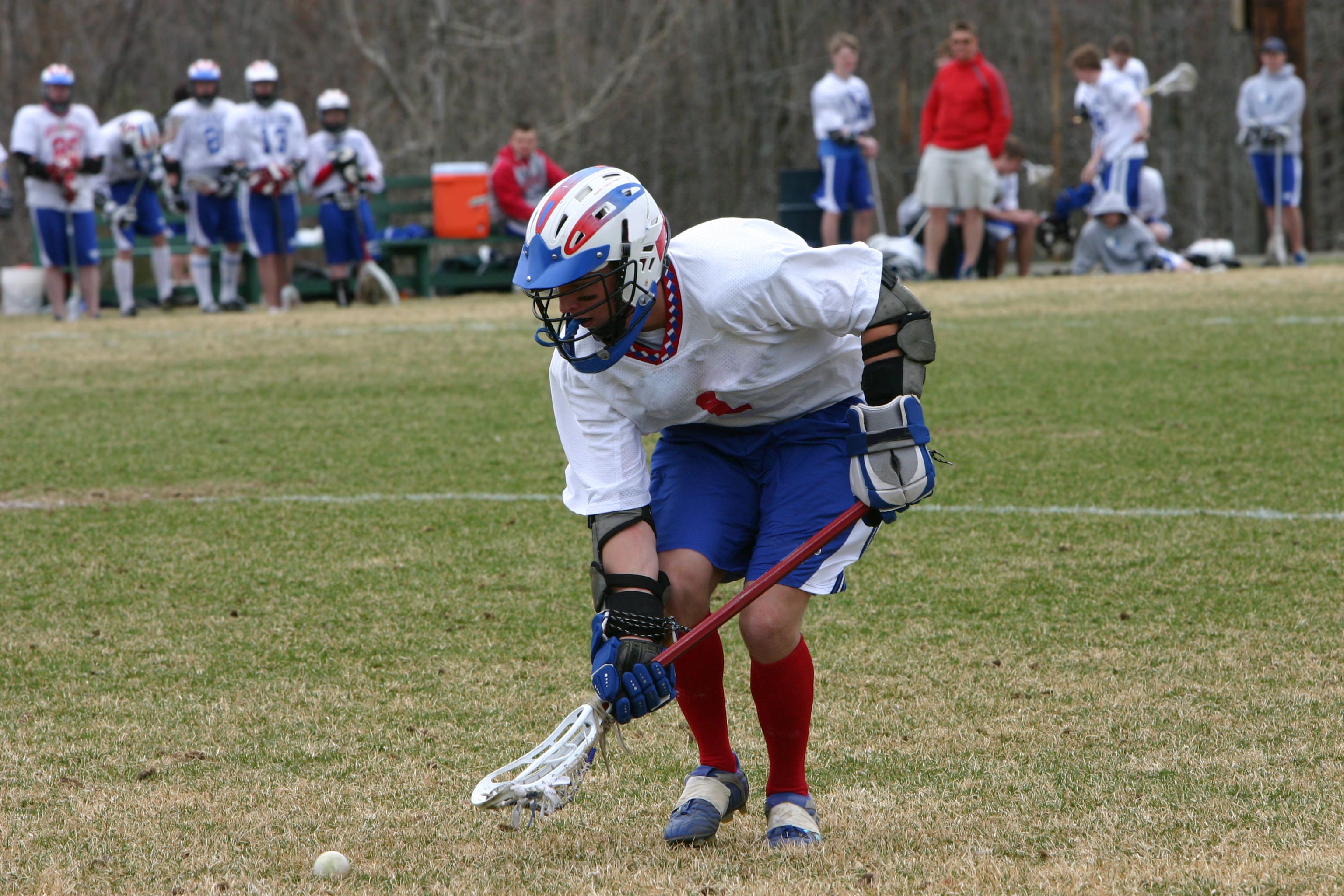 Lacrosse player scooping ball during game.