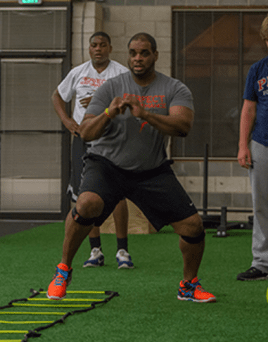 Man exercising with agility ladder indoors.